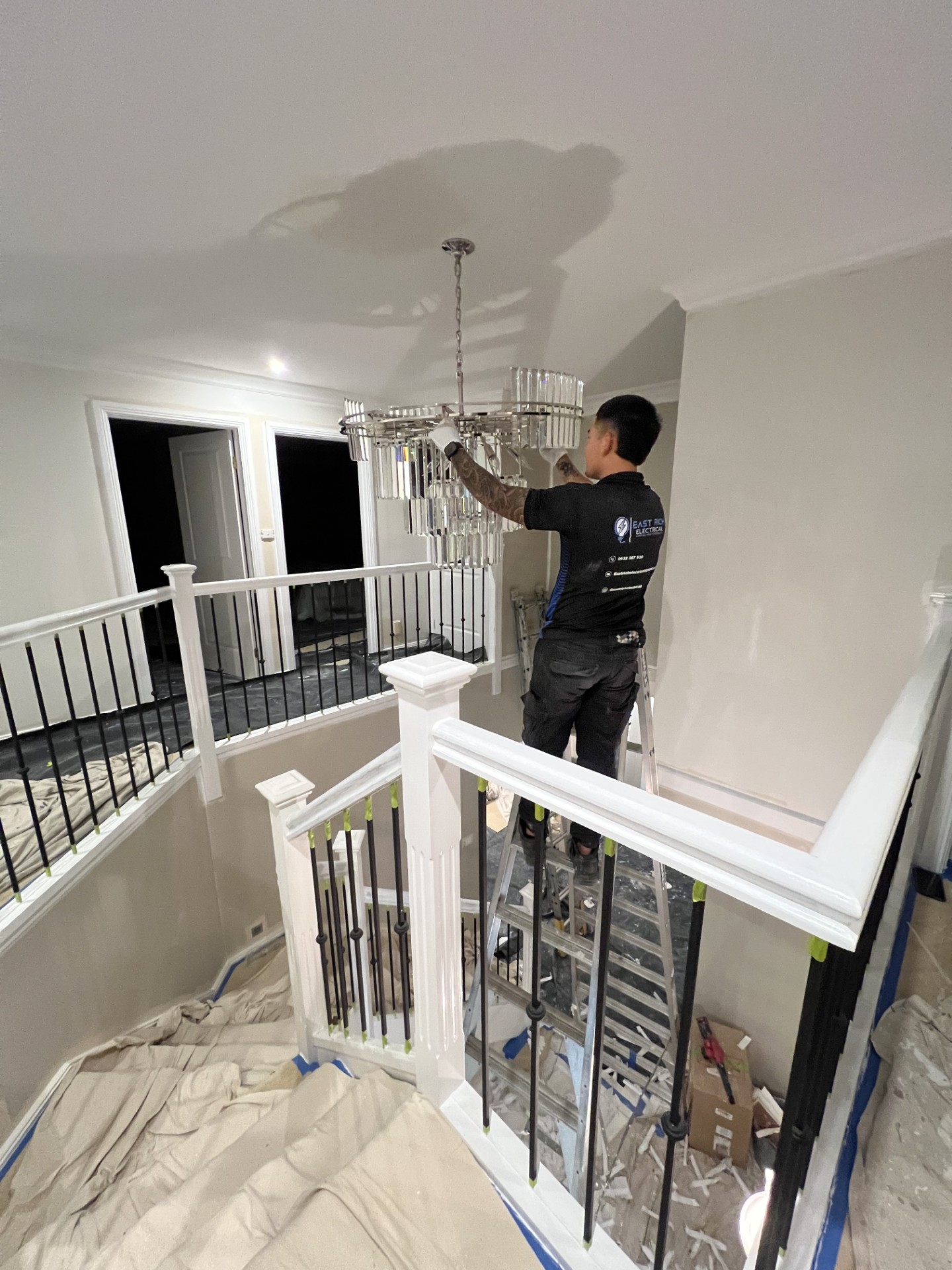 Chandelier Installation - Professional installation of a large multi-tier crystal chandelier in a residential hallway